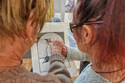 Deux personnes touchent une reproduction sur papier thermogonflé de la sculpture Léda et le cygne de Jean Esprit Marcellin.
