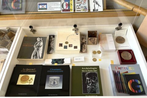 Des produits dérivés et autres catalogues du musée sont présentés dans une vitrine table.